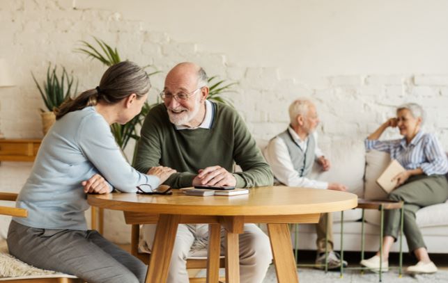 Seniors in senior community socializing on dining table and sofa in background