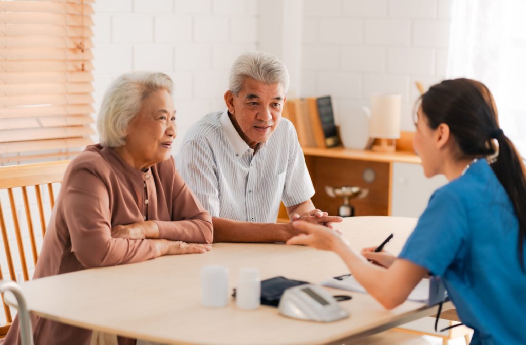 Seniors meeting with a healthcare professional discussing continuous on-site medical care in an assisted living environment.