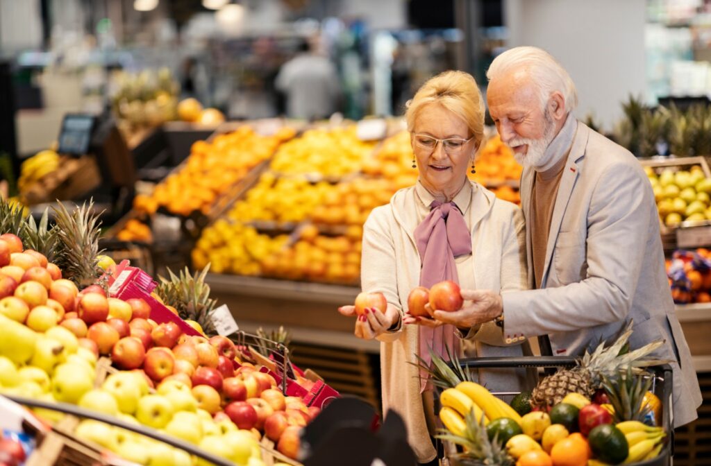 Senior couple grocery shopping together, illustrating independence offered in an assisted living community.