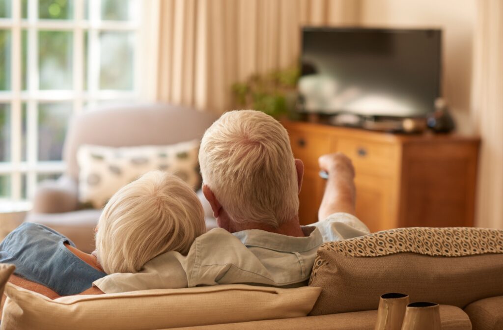 A senior couple cuddle together on a couch as they settle in to watch a movie about Alzheimer’s in the afternoon
