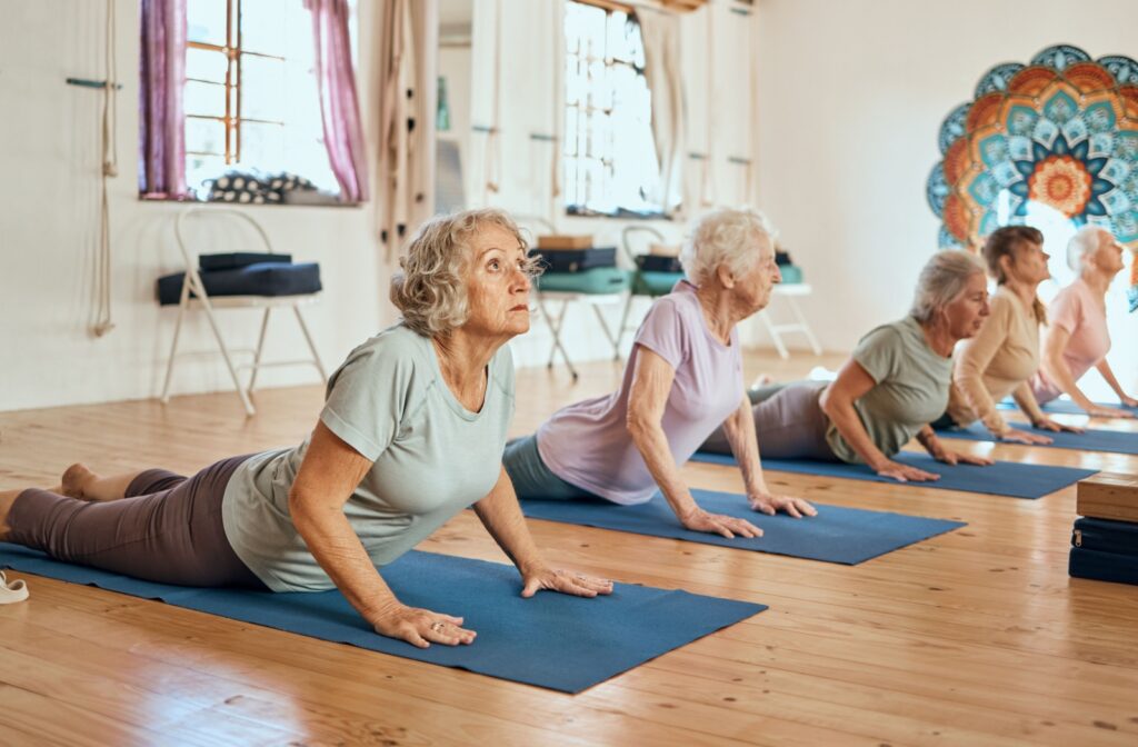 A group of seniors in a community organized yoga class carefully follow instructions to better their balance and flexibility.