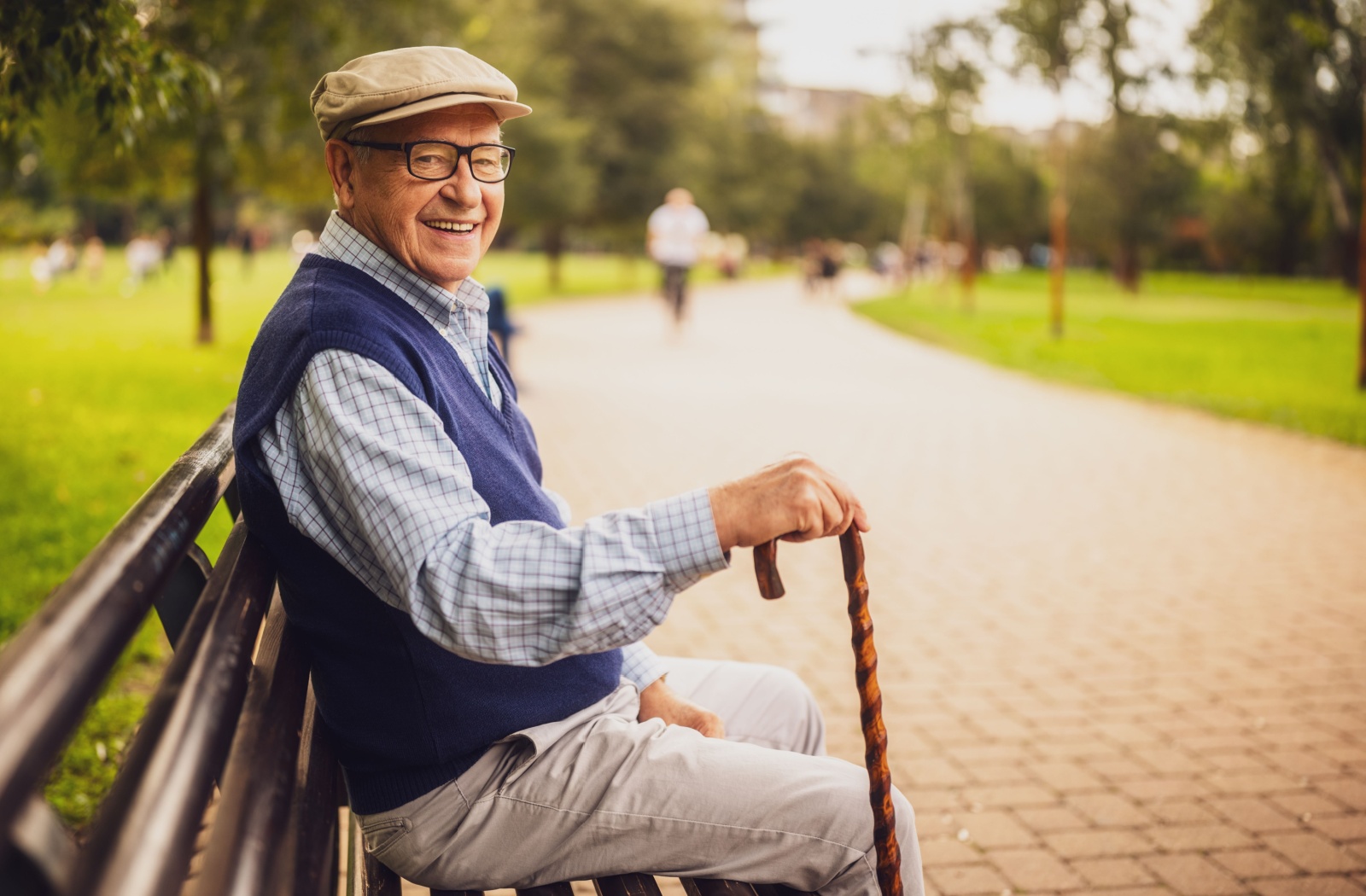 Senior sitting on a park bench, enjoying outdoor time in an assisted living community that supports freedom of movement.