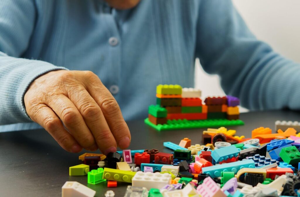 An older adult builds with LEGO in a memory care community.