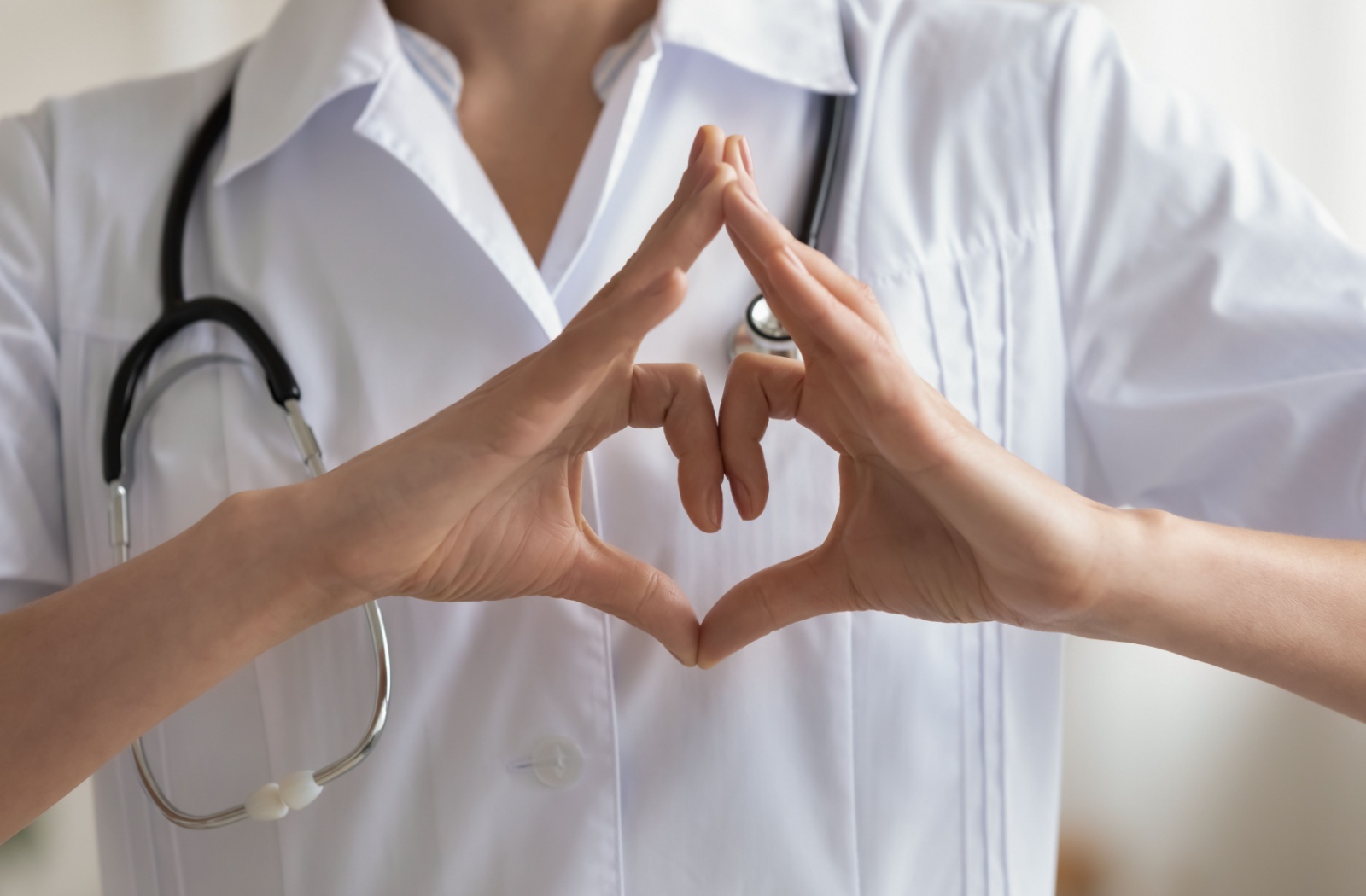 A close-up of a caregiver making a heart shape with their fingers.