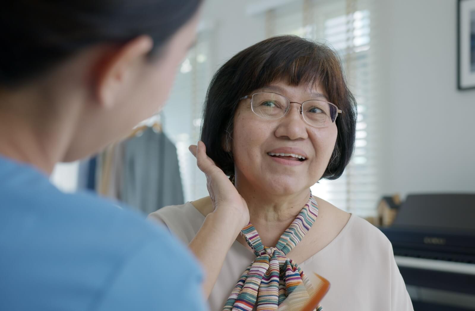 A nurse provides a helping hand to a senior in memory care in getting their outfit and hair ready for the day