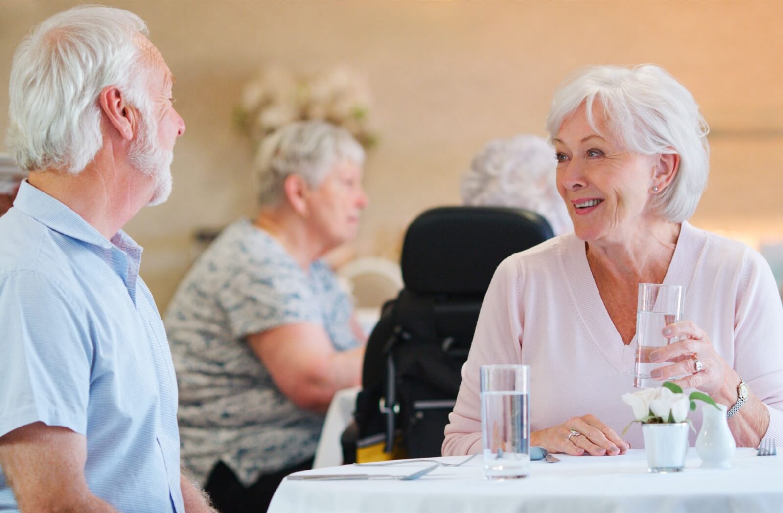 Two seniors chat and drink water to rehydrate before a shared meal in their senior living community